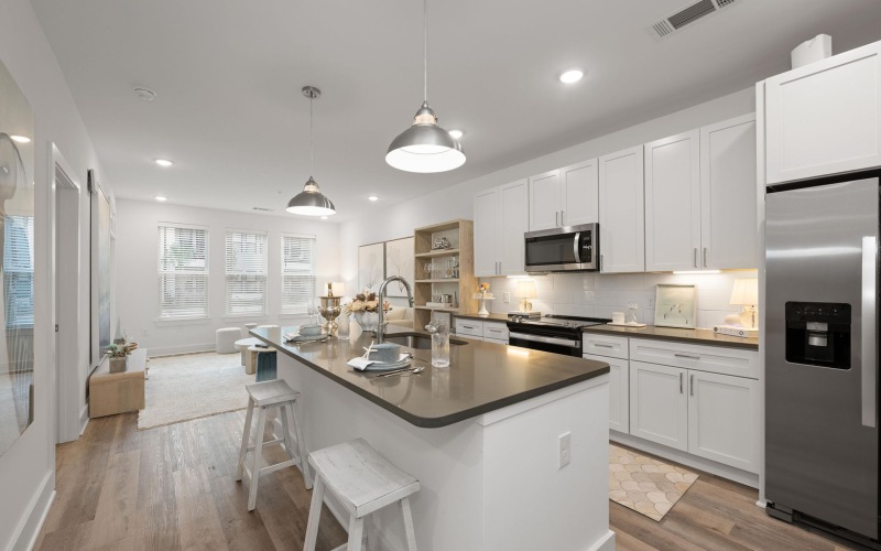 Chef inspired kitchen with gray cabinetry, stainless steel appliances and large island with bar seating