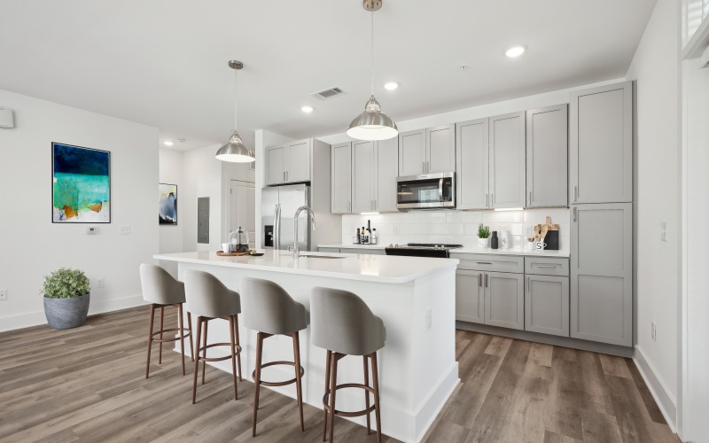 Chef inspired kitchen with gray cabinetry, stainless steel appliances and large island with bar seating